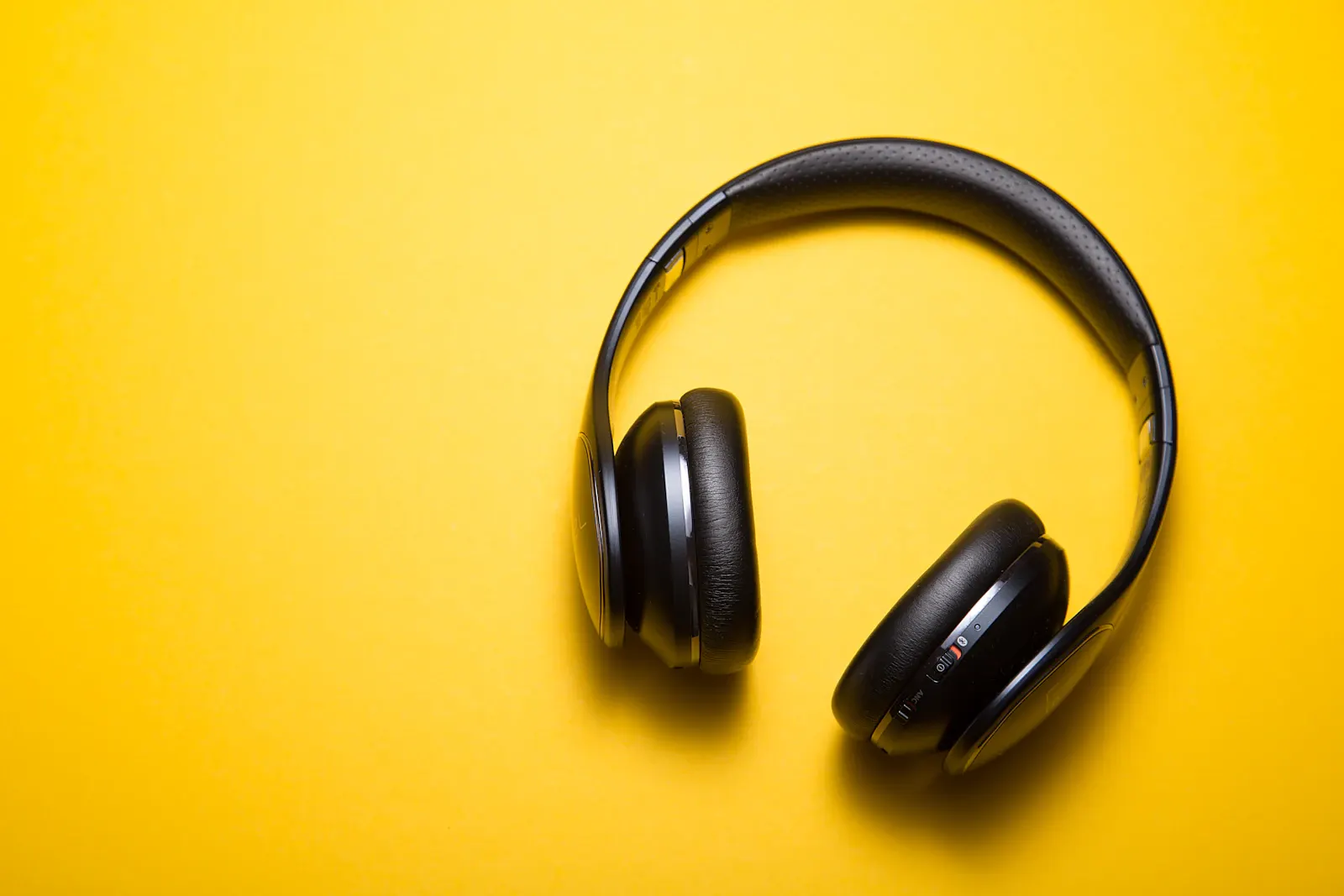 Over-ear headphones photographed against a warm yellow background